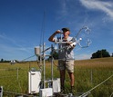 A scientist works on a carbon dioxide flux tower in a field